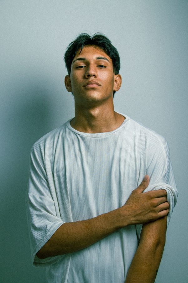 Minimalist portrait of a young man standing with an introspective expression against a white background. Mobile 4K