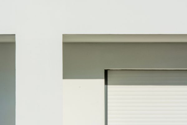 Minimalist white building facade with sunlit shadows creating geometric patterns. Minimaliste 4K