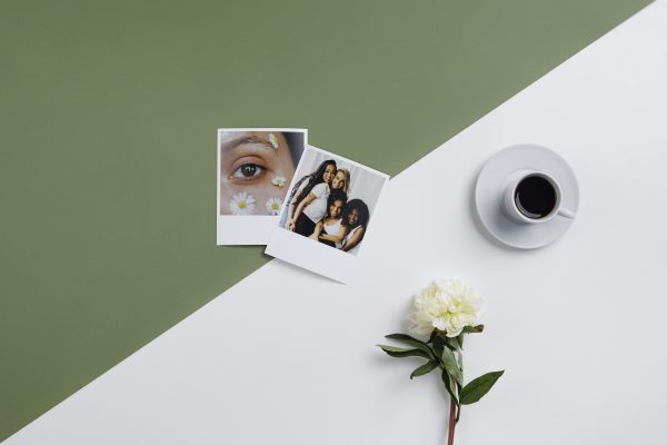 Modern flat lay featuring black coffee, Polaroid photos, and a white flower on a minimalistic backdrop. Minimaliste 4K