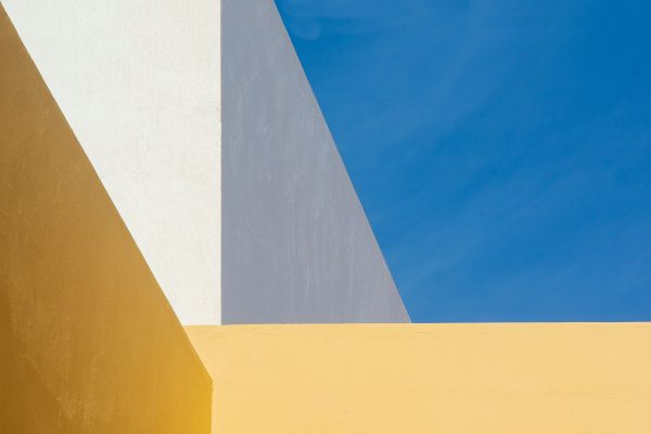 Modern minimalist architecture with bold yellow, white, and blue tones under a clear sky. Minimaliste 4K