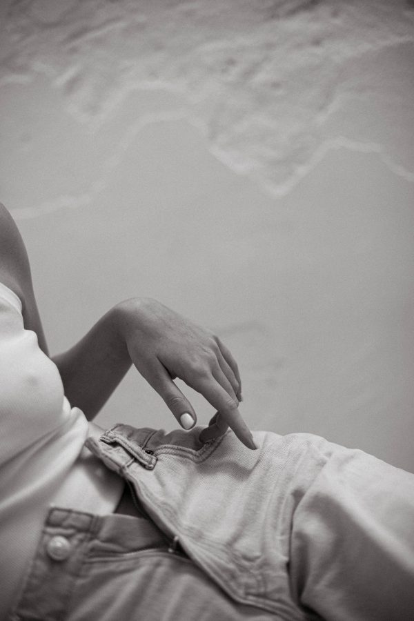 Monochrome close-up of a stylish hand on denim clothing. Mobile 4K