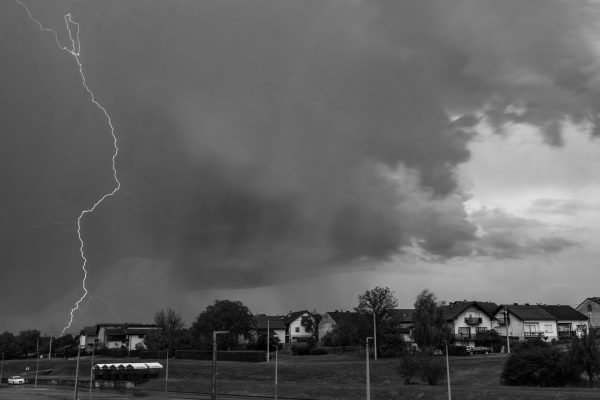 Monochrome image capturing a dramatic lightning strike during a thunderstorm over a neighborhood. Dark 4K