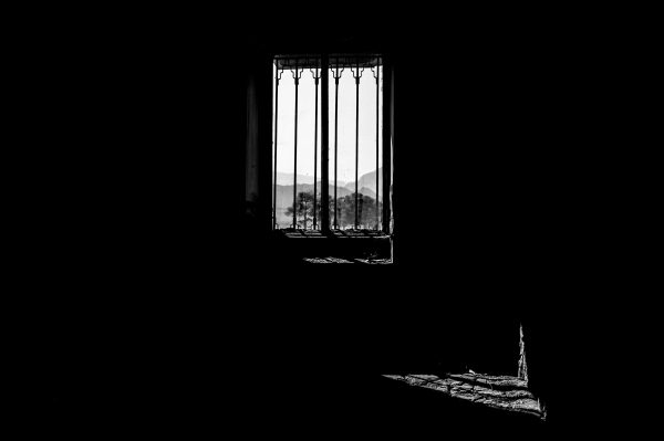 Monochrome shot of a window silhouette overlooking mountains, exuding a dramatic and moody atmosphere. Dark 4K