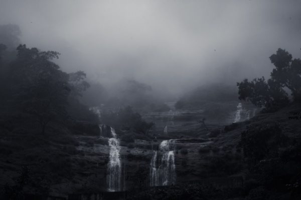 Mysterious waterfall shrouded in mist, creating a moody and serene landscape. Nature 4K