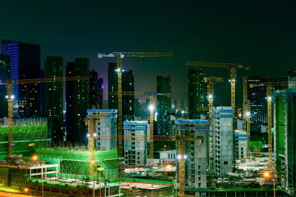 Night view of a bustling construction site in an urban cityscape with cranes and high-rise buildings. Architecture 4K