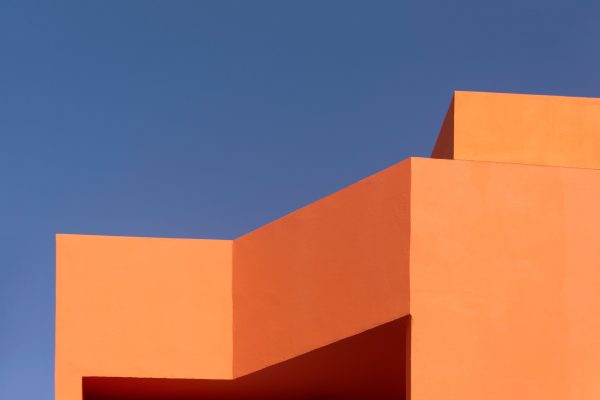 Orange geometric architecture with a minimalist design contrasts sharply with a deep blue sky. Minimaliste 4K