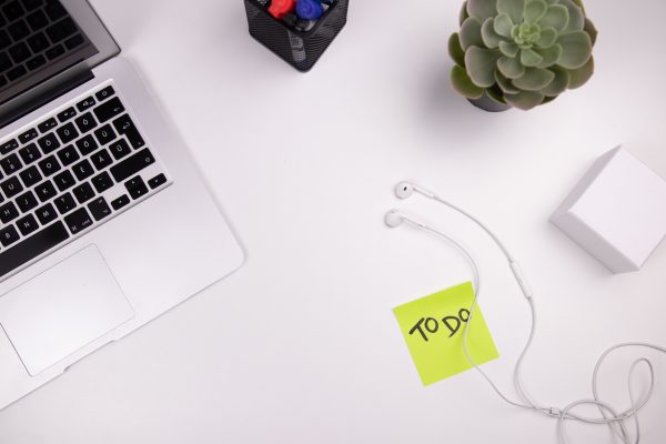 Organized workspace featuring a laptop, earphones, and a to-do list with plant decor. Minimaliste 4K