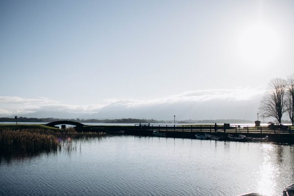 Peaceful lake landscape with a pier and boats under a clear sky during sunset. Nature 4K