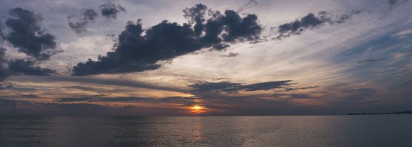 Peaceful ocean sunset with a dramatic sky and silhouette clouds over calm water. Nature 4K