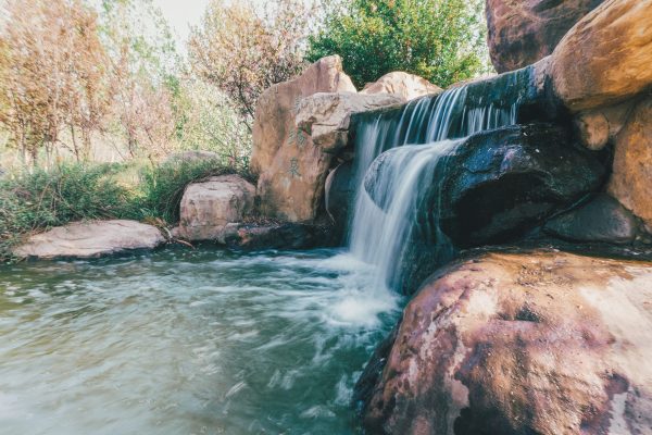 Peaceful waterfall cascading over rocks surrounded by lush foliage. Nature 4K