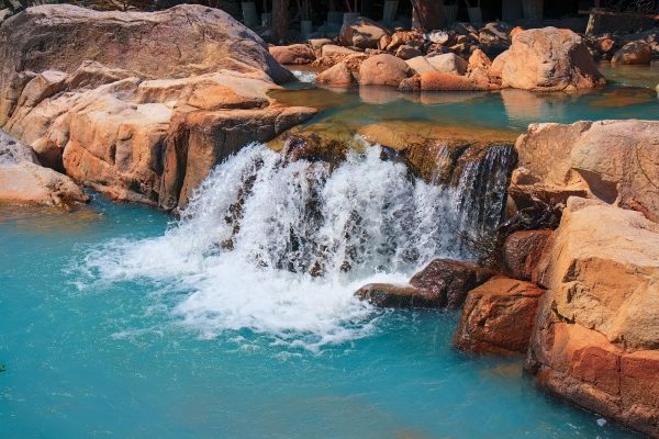 Peaceful waterfall flows over rocks into a turquoise pool in a natural setting. Nature 4K