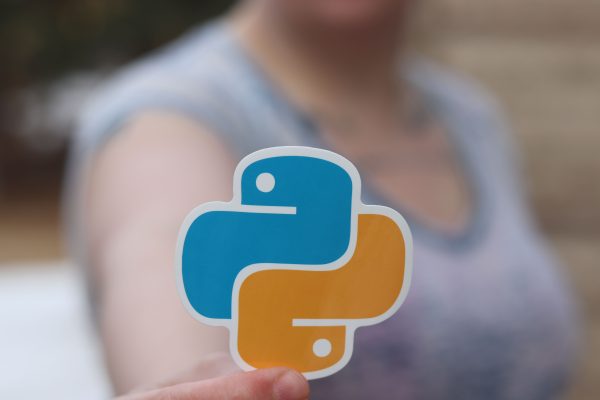 Person holding Python logo sticker with blurred background, highlighting programming focus. Wallpaper 4K