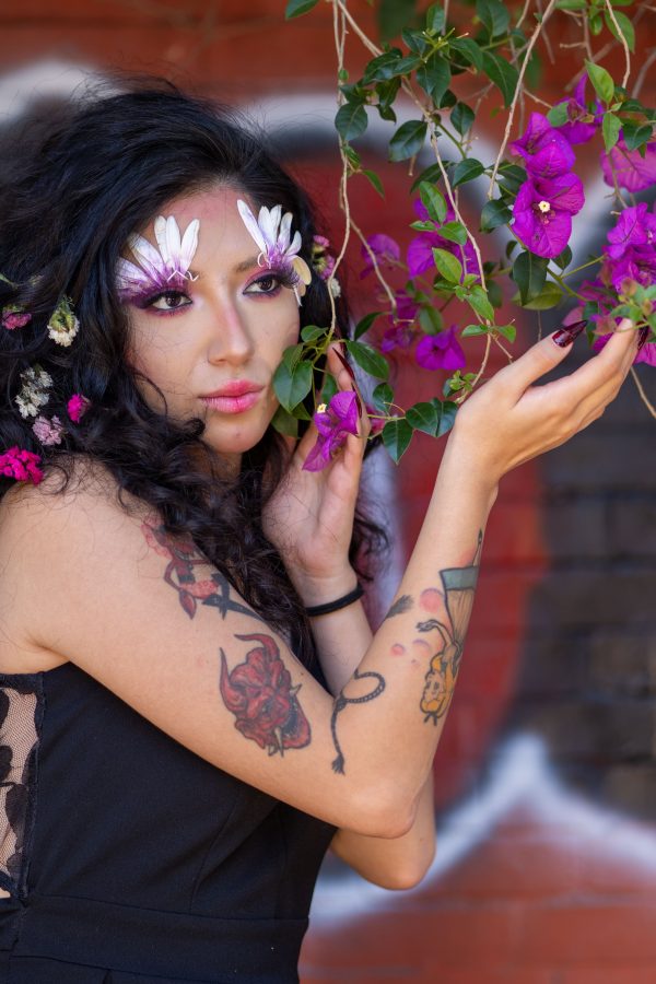 Portrait of a Latina woman with floral artistic makeup, showcasing vibrant flowers and tattoos in an outdoor setting. Mobile 4K
