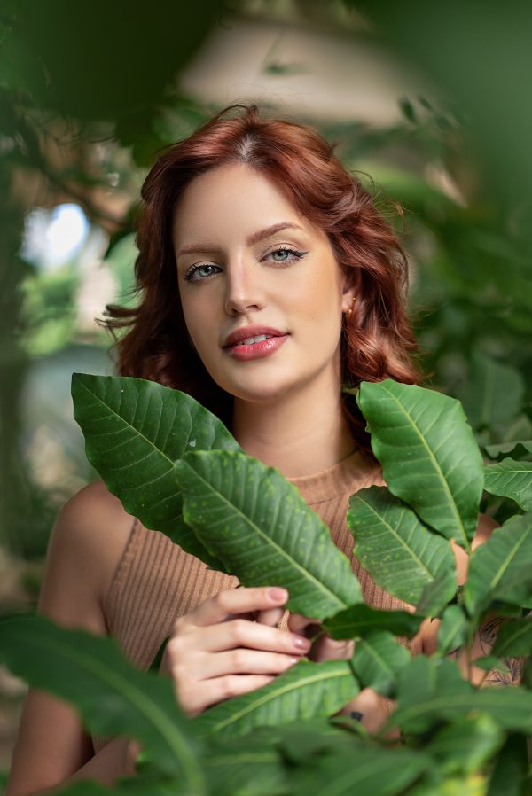 Portrait of a redhead woman surrounded by vibrant green leaves in Belo Horizonte, Brazil. Mobile 4K