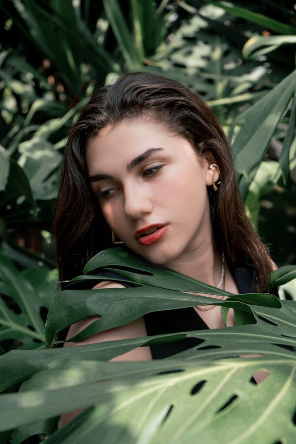 Portrait of a woman amidst tropical leaves, exuding a serene and natural vibe. Mobile 4K