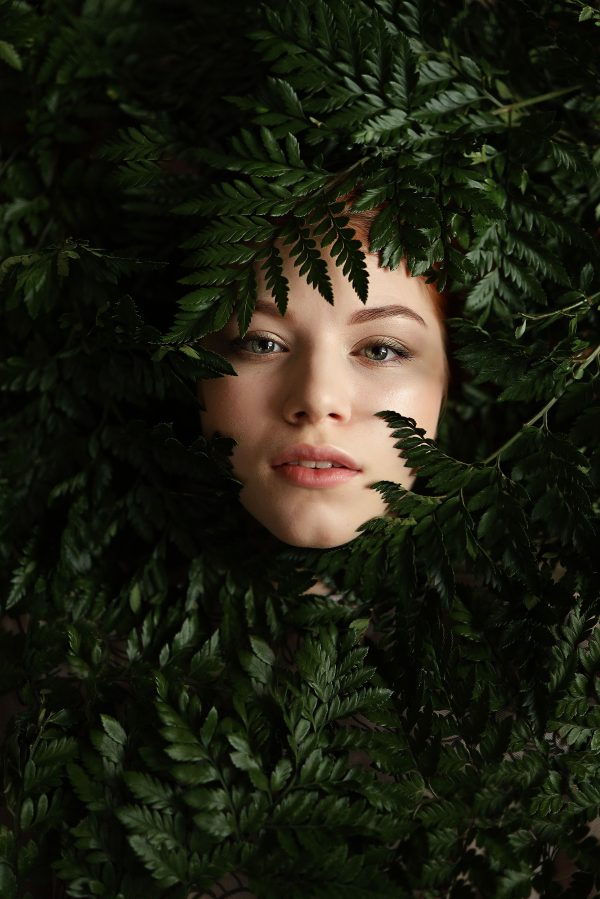 Portrait of a woman among lush green ferns, blending nature and beauty for a captivating studio composition. Mobile 4K