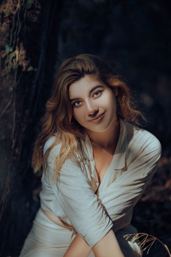 Portrait of a woman in sunlight, surrounded by forest foliage, capturing a serene nature vibe. Mobile 4K