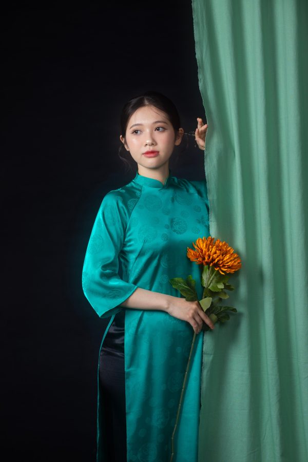 Portrait of a young Vietnamese woman in traditional ao dai, holding flowers and posing against a curtain. Mobile 4K