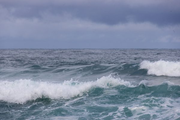 Powerful ocean waves crash beneath a moody, overcast sky, showcasing nature's raw energy. Nature 4K