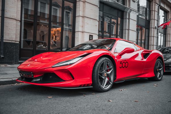 Red luxury sports car parked on an urban street, showcasing modern automotive design. Voitures 4K