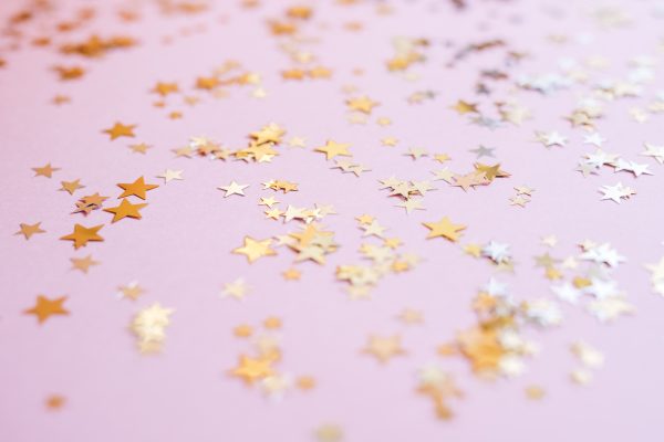 Scattered gold star confetti on a soft pink background for festive celebrations. Espace 4K