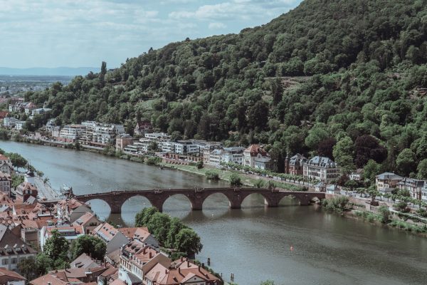 Scenic aerial view of Heidelberg, showcasing its historic bridge over the Neckar River surrounded by lush hills. Architecture 4K