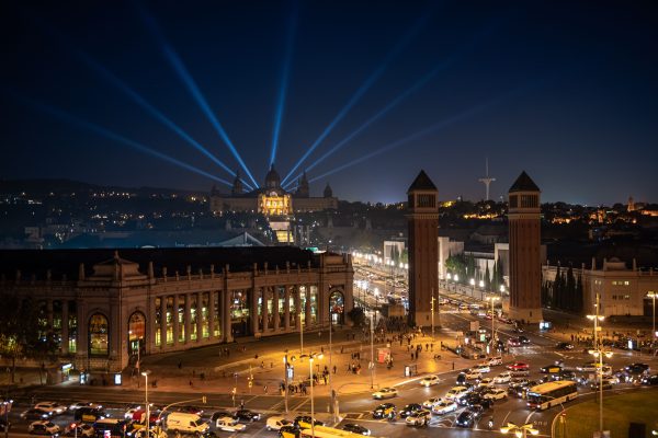 Scenic nighttime view of Barcelona's landmarks with vibrant streetlights and laser beams in the sky. Voitures 4K