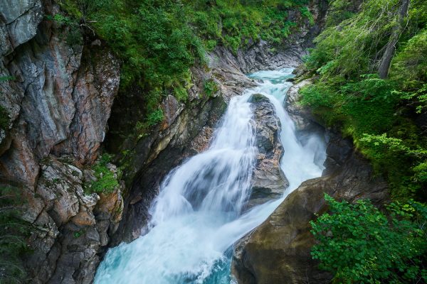 Scenic view of Krimml waterfall cascading through rocky terrain in lush Austrian forest. Nature 4K