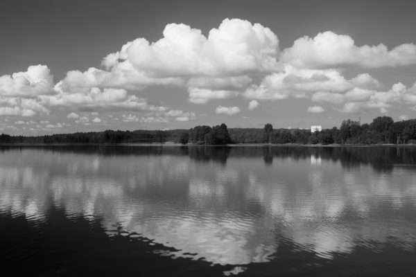 Serene black and white landscape of a reflective lake under fluffy clouds in Jönköping, Sweden. Nature 4K