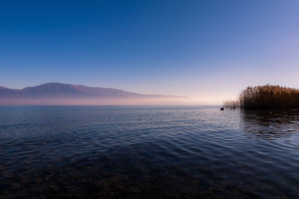 Serene sunset over a tranquil lake with distant mountains in Albania. Nature 4K