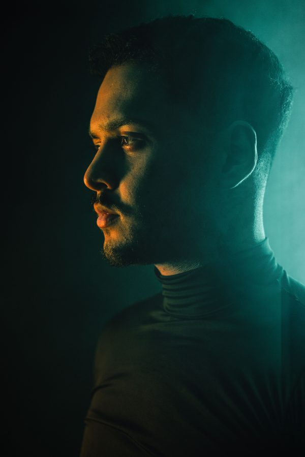Side profile portrait of a man with dramatic lighting creating a moody atmosphere. Mobile 4K