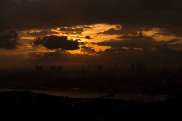 Silhouette of a cityscape under a dramatic sunset sky with dark clouds. Dark 4K