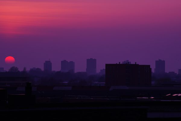 Silhouetted city skyline at sunset with a dramatic purple and orange sky. Architecture 4K