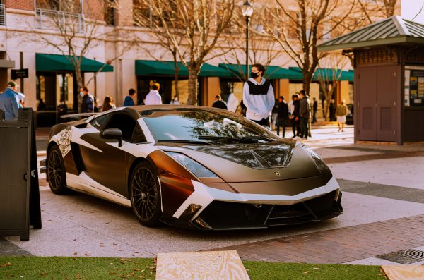 Sleek Lamborghini Gallardo parked outdoors with people in background, urban setting. Voitures 4K