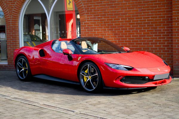 Sleek red Ferrari sports car parked outdoors with brick façade background. Voitures 4K