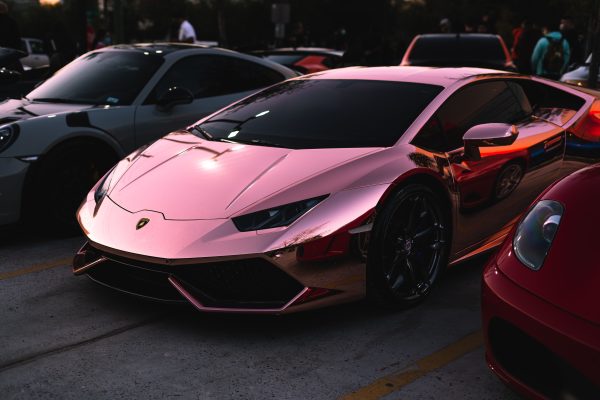 Sleek rose gold Lamborghini shining at an outdoor car show, epitome of luxury and power. Voitures 4K
