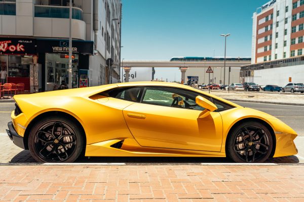 Sleek yellow sports car parked on a sunny day in the vibrant streets of Dubai. Voitures 4K