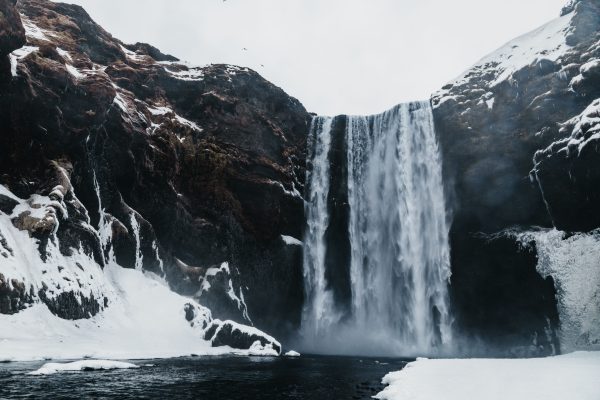 Spectacular view of rapid waterfall in mounts near river and snowy surface under sky in wintertime Nature 4K