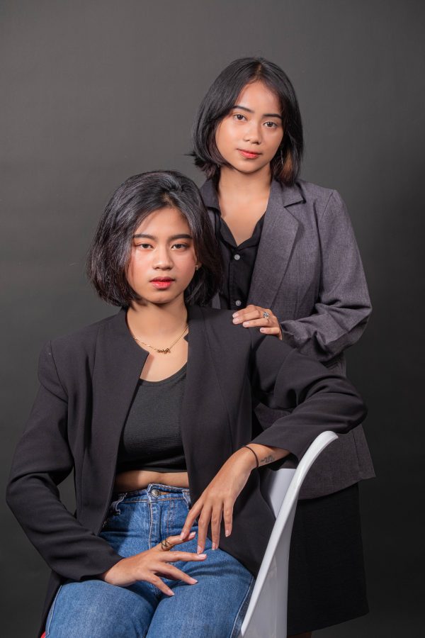 Studio portrait of two women in business blazers posing confidently against a dark backdrop. Mobile 4K