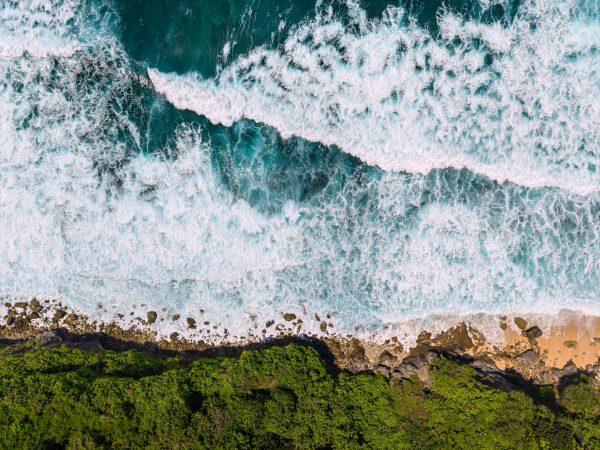 Stunning aerial view capturing Bali's vibrant coastline with lush greenery and crashing waves. Nature 4K