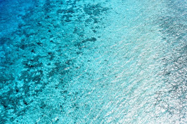 Stunning aerial view of clear blue ocean water with vibrant turquoise hues. Nature 4K