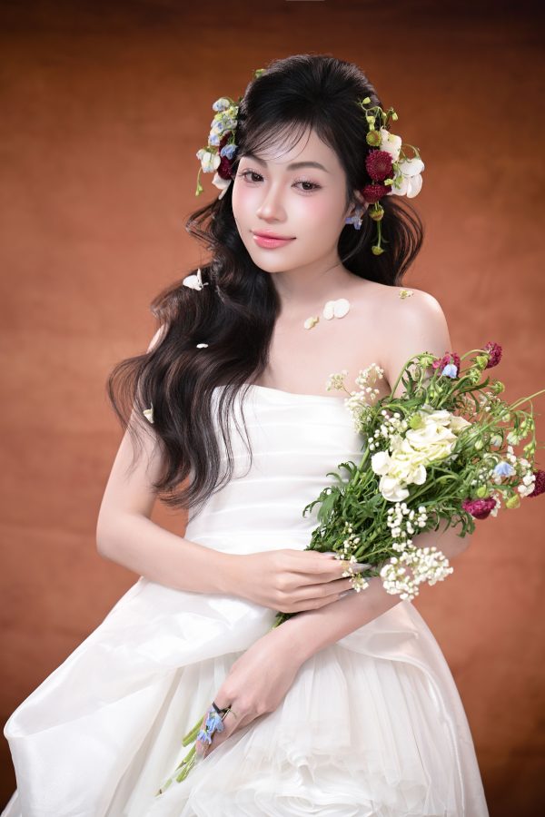 Stunning bridal portrait of a woman in a white gown holding a floral bouquet, adorned with flowers in her hair. Mobile 4K