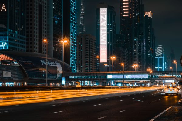Stunning night shot of Dubai's illuminated skyline with light trails on a bustling highway. Voitures 4K
