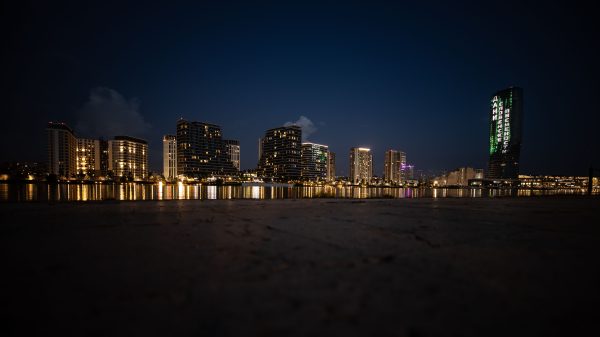 Stunning night view of illuminated skyscrapers reflecting on water, showcasing urban beauty. Architecture 4K