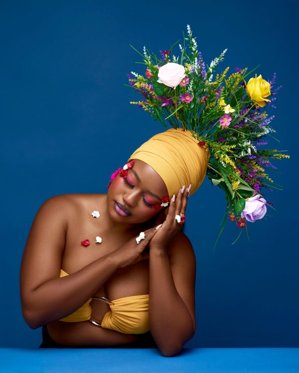 Stunning portrait of woman with vibrant flower crown and makeup against blue background. Mobile 4K