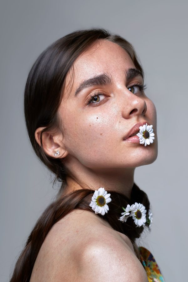 Stunning studio portrait of a woman with daisies adorning her hair, showcasing natural beauty and elegance. Mobile 4K