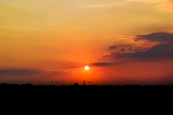 Stunning sunset view with vibrant orange and yellow hues over a silhouetted city skyline. Nature 4K
