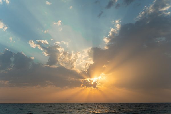Stunning sunset with sun rays breaking through clouds over the ocean near Alakhadzi. Nature 4K