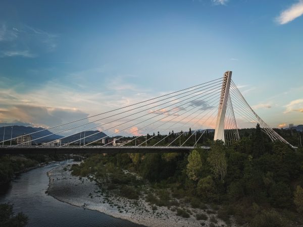 Stunning view of a cable-stayed bridge spanning over a river with scenic background. Architecture 4K