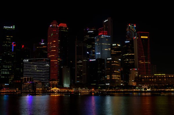 Stunning view of illuminated Singapore skyline reflecting on water during nighttime. Architecture 4K
